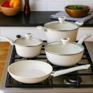 Full 7-piece grey marble-coated forged aluminum cookware set with glass lids, shown on a kitchen counter in the UAE.