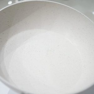 Extreme close-up of the speckled grey marble non-stick surface, highlighting the scratch-resistant texture.